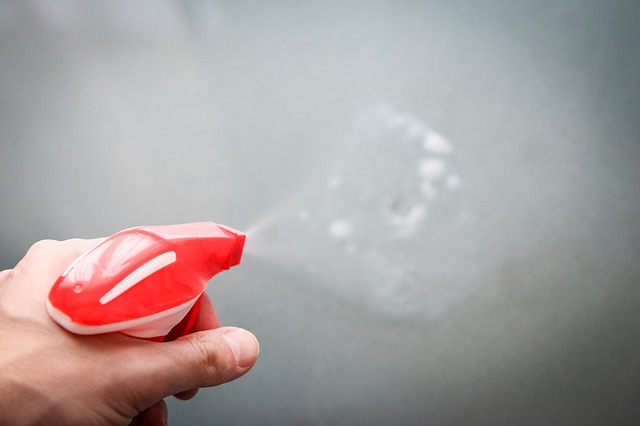 Hand spraying anti-bacterial spray to clean a surface