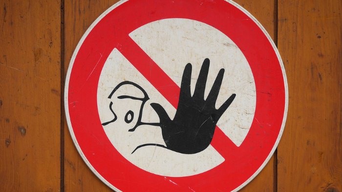 Red and white safety sign featuring a hand symbol indicating warning