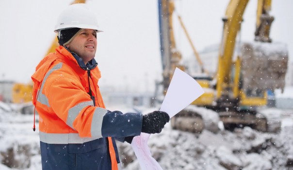 Site worker wearing safety gear holding winter workwear guide