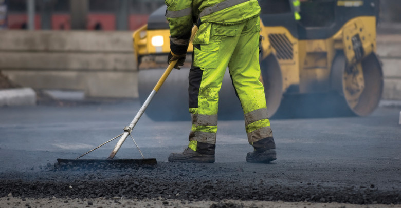 Man wearing yellow hi-vis workwear fixing the road