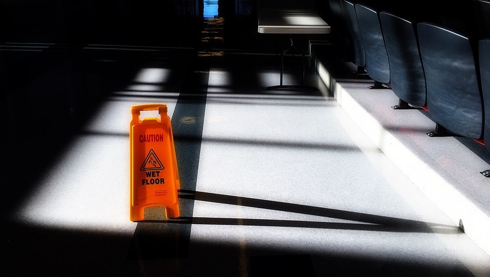 Orange caution wet floor sign placed on floor to alert risk of slipping in the area