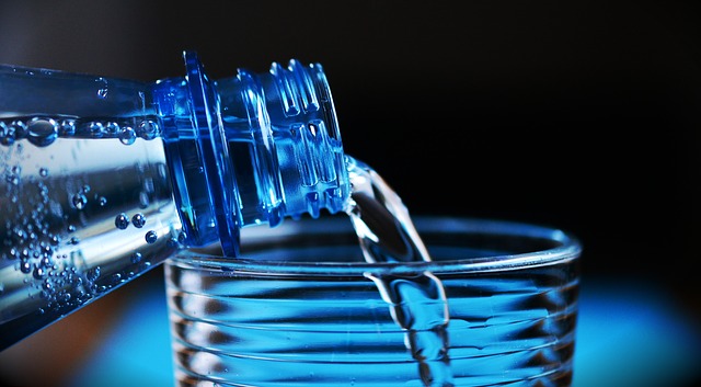 A bottle of water being poured into a glass