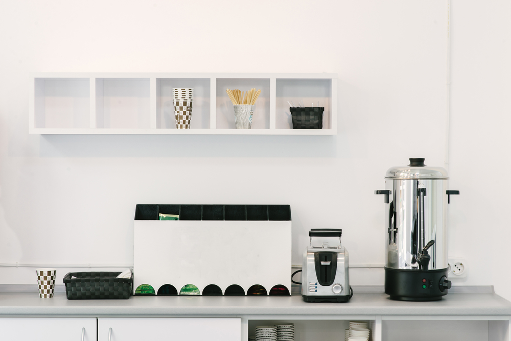 White kitchen countertop displaying coffee machine, cups, and assorted kitchen items