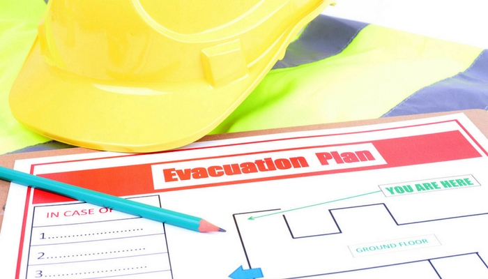 Yellow hard hat with example evacuation plan and blue pencil